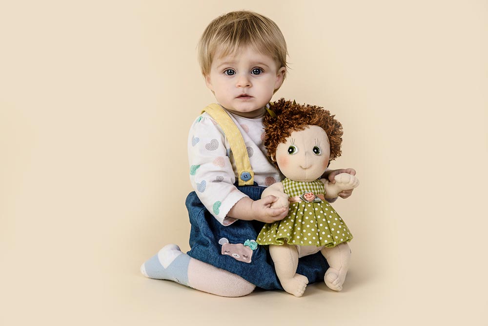 Baby posing with a doll for a baby portrait