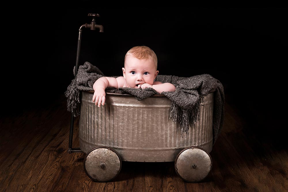 cute baby portrait posing in a metal bath tub
