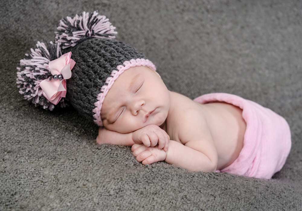 Newborn baby with grey hat on asleep for a baby photoshoot