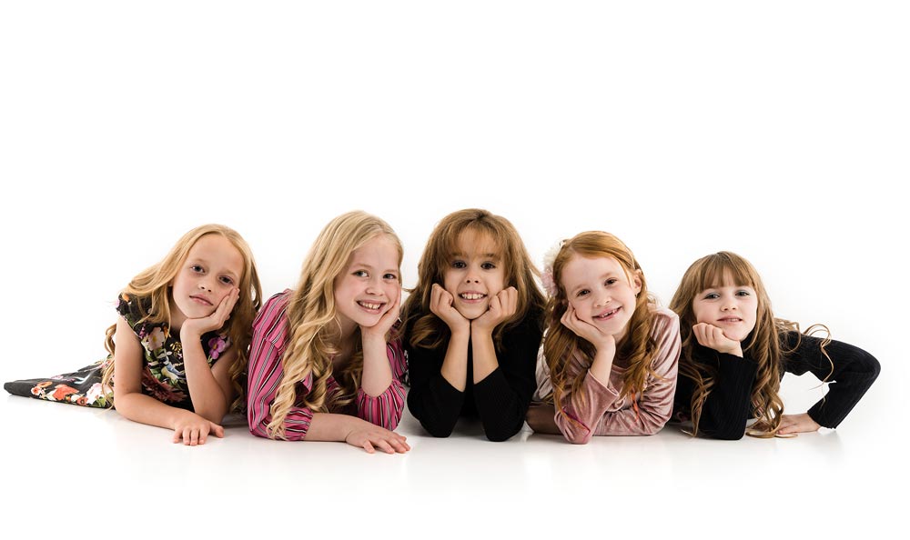 5 girls laid down next to each other smiling Posing at a children's photoshoot party in Chesterfield