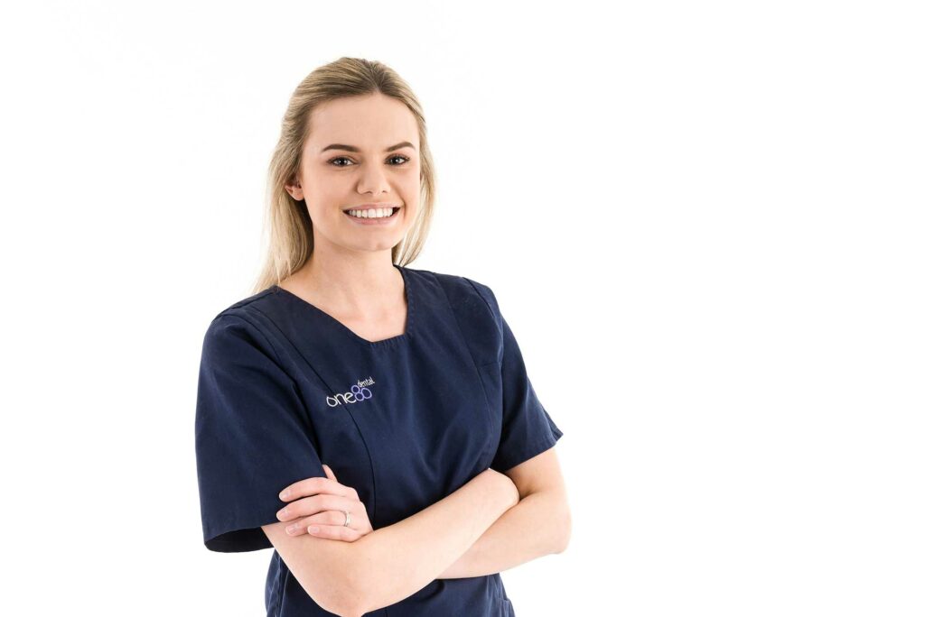 Female smiling with arms folded in a dental uniform for meet our staff corporate headshot photography