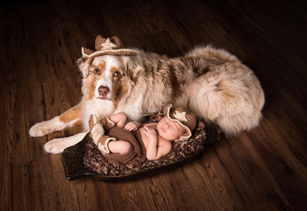 Newborn baby asleep next to a pet dog with the same hats on