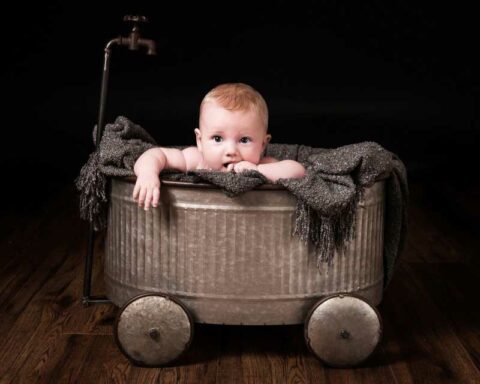 newborn baby in a metal small bathtub for a newborn photography session