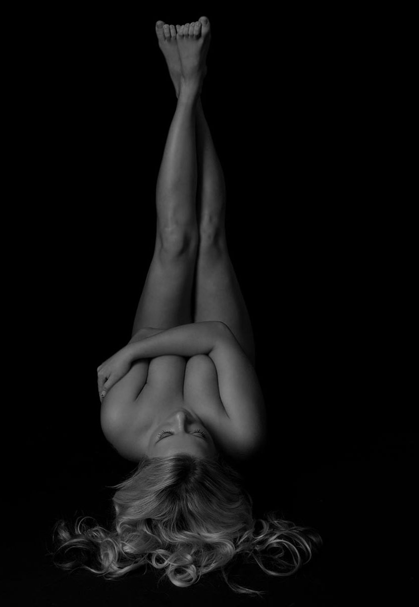 Lady laid down with her feet posing for a boudoir photoshoot experience in black & white