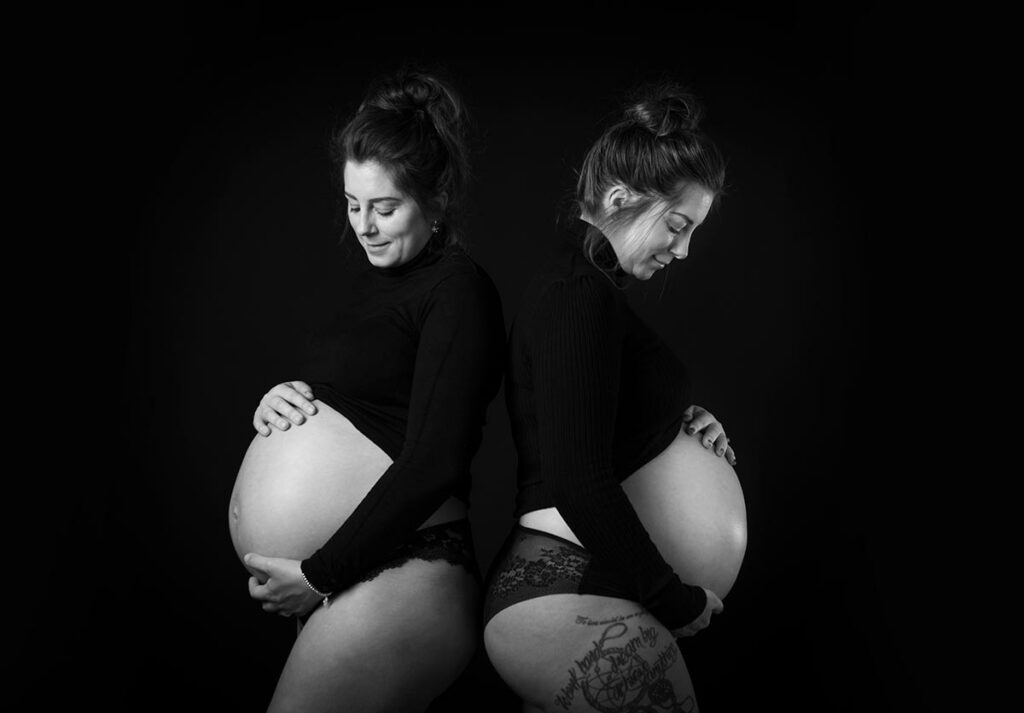 two ladies with black jumpers showing their baby bumps for maternity photography
