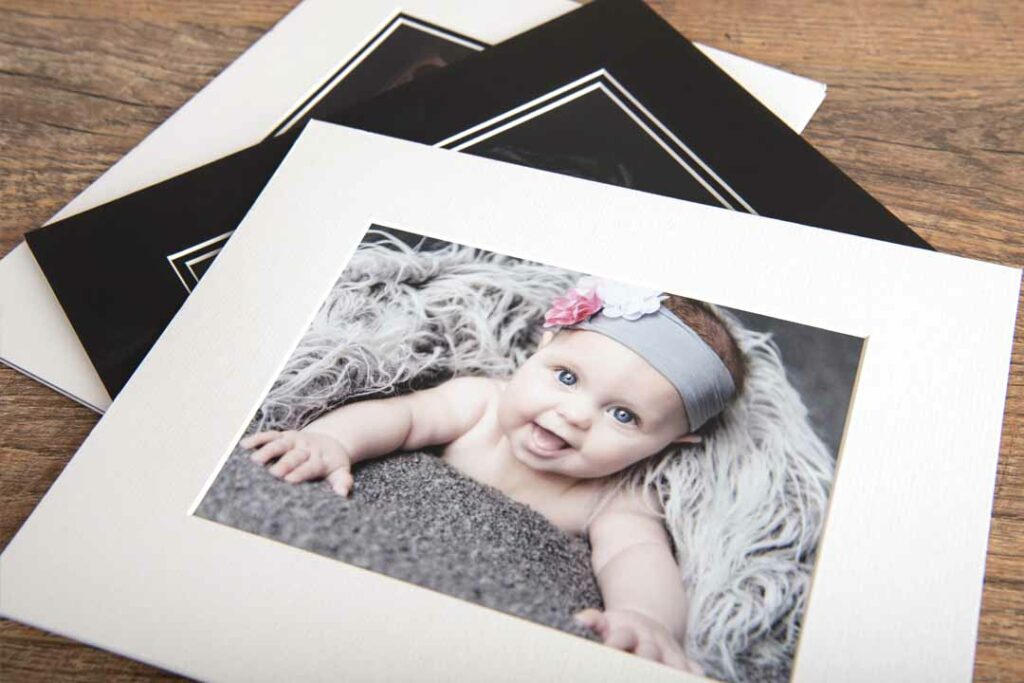 image showing multiple images laid out all with mounts, the most visible image has a picture from a newborn photoshoot on top