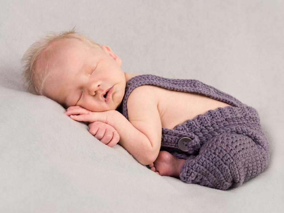 a newborn baby sleeping and posed for a newborn baby photoshoot